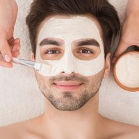 Unshaven man having cosmetic mask in spa salon, top view